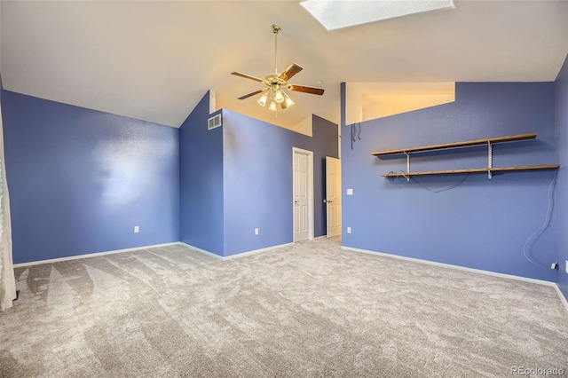 carpeted empty room with a skylight, ceiling fan, and high vaulted ceiling