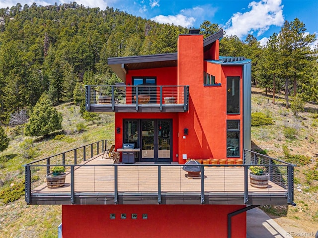 5896 Peregrine Trl, Golden, CO 80403 - rear view of property with a balcony, a wooded view, a chimney, stucco siding, and french doors