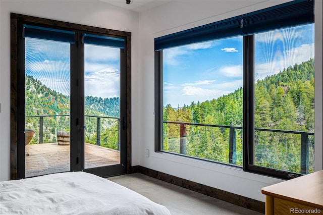 5896 Peregrine Trl, Golden, CO 80403 - bedroom featuring access to exterior, multiple windows, and a view of trees