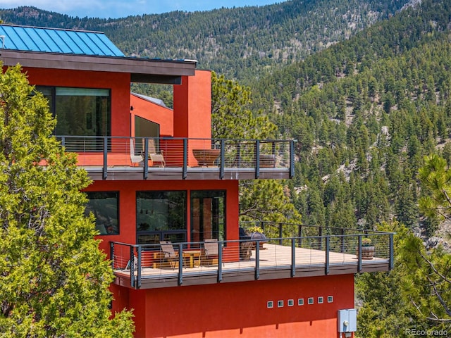 5896 Peregrine Trl, Golden, CO 80403 - back of property featuring a balcony, a view of trees, a mountain view, stucco siding, and a standing seam roof