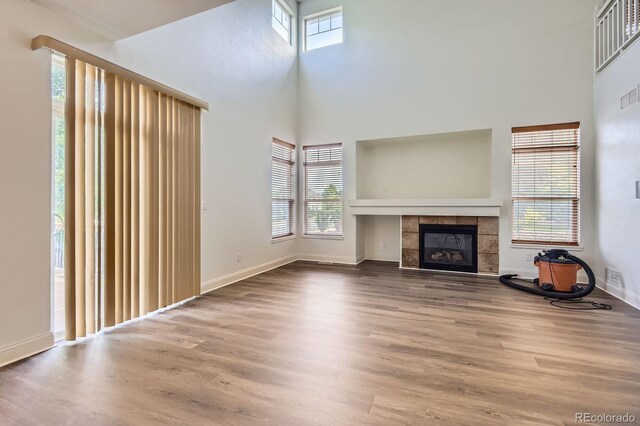19259 E Caspian Pl, Aurora, CO 80013 - unfurnished living room with wood finished floors, a tiled fireplace, and a high ceiling