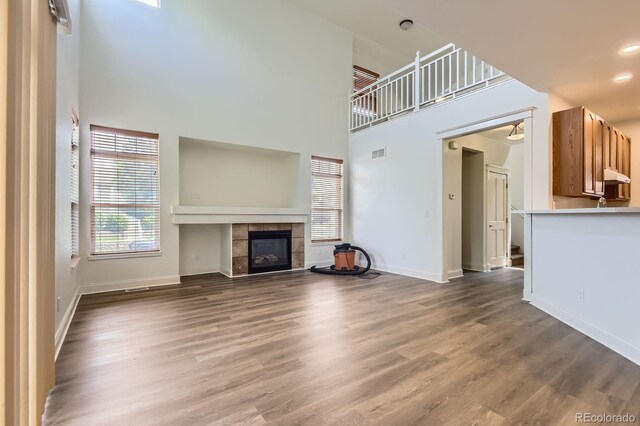 19259 E Caspian Pl, Aurora, CO 80013 - unfurnished living room featuring a towering ceiling, a fireplace, and wood finished floors