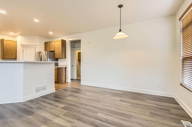 19259 E Caspian Pl, Aurora, CO 80013 - kitchen featuring freestanding refrigerator, wood finished floors, recessed lighting, hanging light fixtures, and light countertops