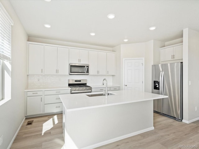 kitchen featuring sink, white cabinetry, appliances with stainless steel finishes, and an island with sink