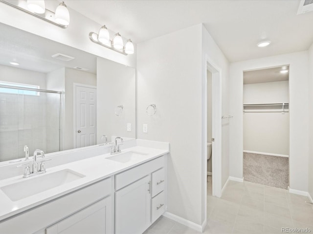 bathroom featuring tile patterned floors, toilet, vanity, and walk in shower