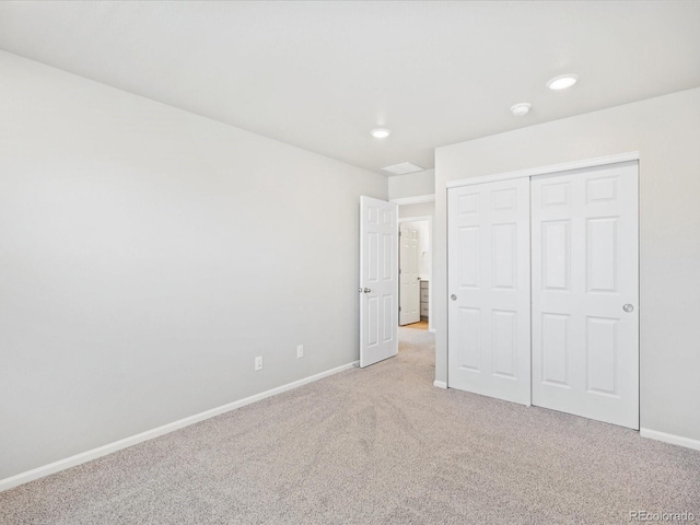 unfurnished bedroom with light colored carpet and a closet