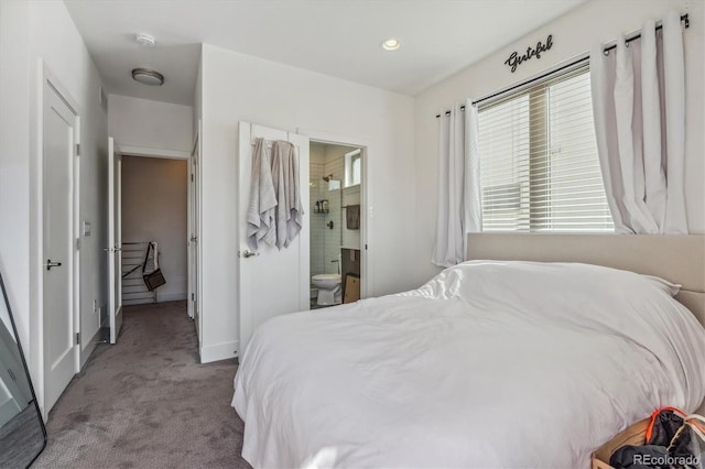 bedroom with connected bathroom and light carpet