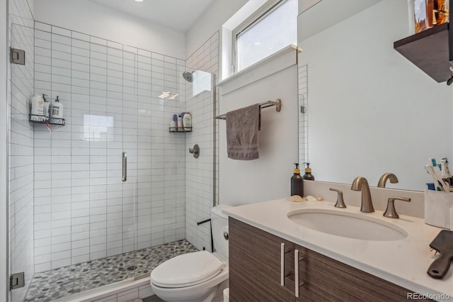 bathroom with toilet, vanity, and a shower with shower door