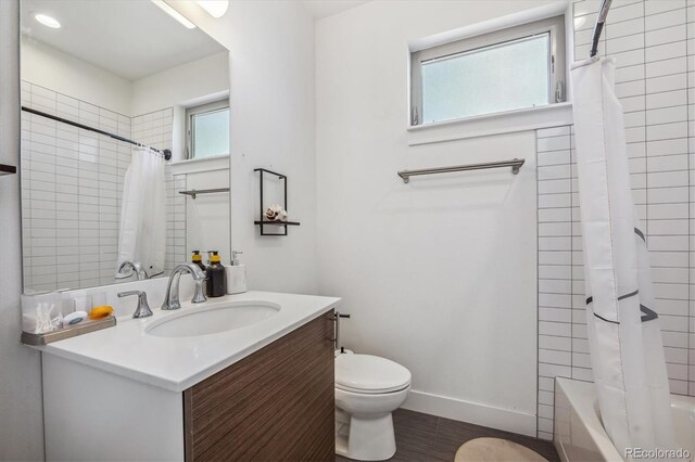 full bathroom featuring toilet, hardwood / wood-style floors, shower / bath combination with curtain, and vanity