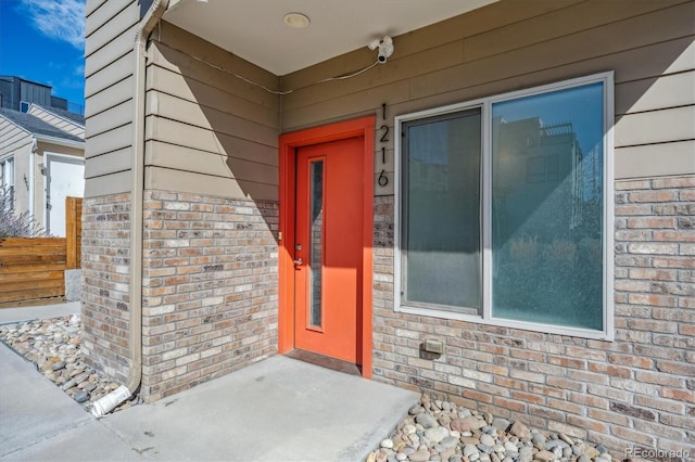 entrance to property featuring brick siding and fence