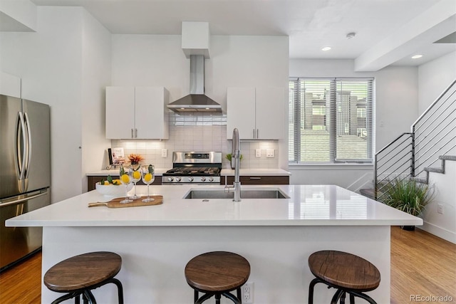 1216 Perry St, Denver, CO 80204 - kitchen with appliances with stainless steel finishes, wall chimney exhaust hood, a breakfast bar, light countertops, and recessed lighting