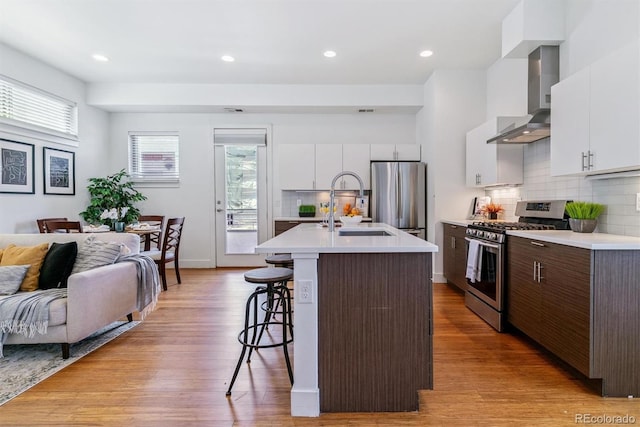 1216 Perry St, Denver, CO 80204 - kitchen featuring stainless steel appliances, wall chimney exhaust hood, a breakfast bar, light countertops, and recessed lighting