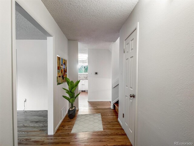 13561 W Alaska Pl, Lakewood, CO 80228 - hallway featuring visible vents, a textured ceiling, baseboards, and wood finished floors