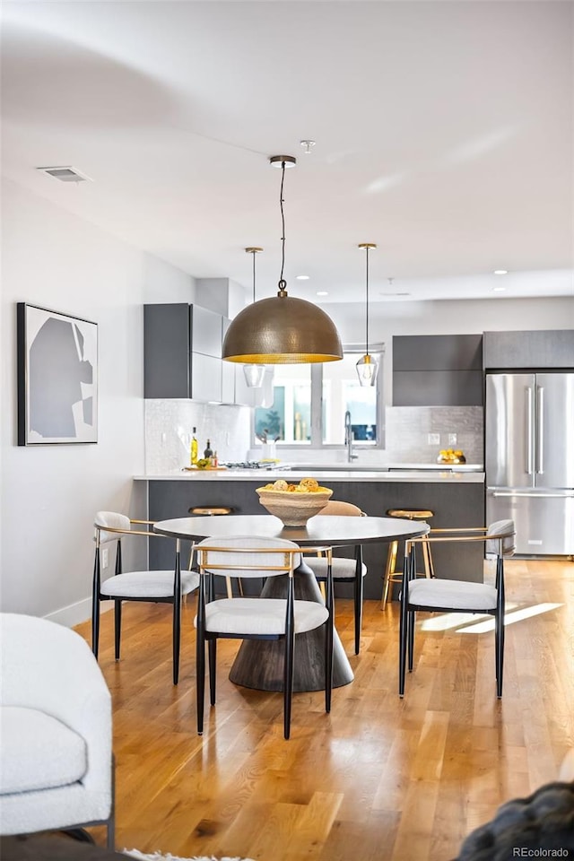 dining area featuring light wood-style flooring and visible vents