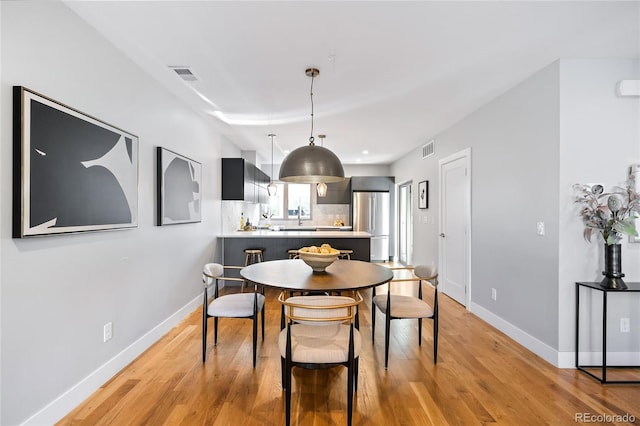 dining space featuring light wood-type flooring, visible vents, and baseboards