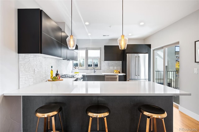 kitchen with a breakfast bar area, stainless steel appliances, light countertops, and modern cabinets