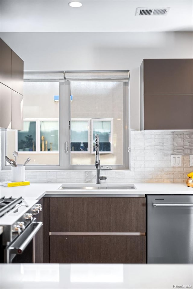 kitchen with visible vents, a sink, decorative backsplash, stainless steel appliances, and modern cabinets