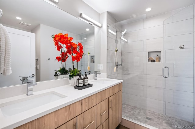 bathroom with double vanity, visible vents, a stall shower, and a sink