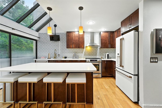 960 N Pennsylvania St Unit 6, Denver, CO 80203 - kitchen with high end white refrigerator, wall chimney exhaust hood, stainless steel range, light countertops, and decorative backsplash