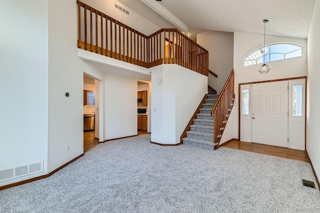 entrance foyer featuring carpet floors, high vaulted ceiling, and visible vents