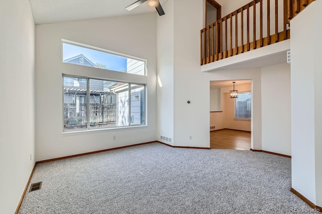 unfurnished living room with high vaulted ceiling, visible vents, and carpet