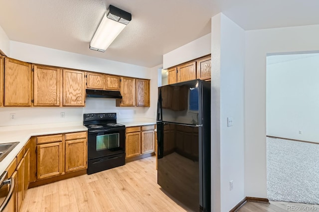 kitchen with black appliances, brown cabinets, and under cabinet range hood