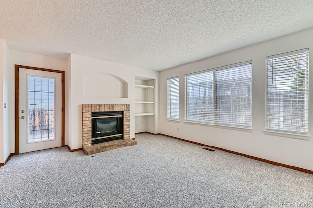unfurnished living room featuring carpet floors, a brick fireplace, built in features, baseboards, and visible vents