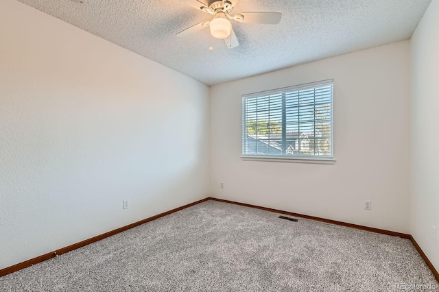 carpeted spare room with visible vents, a textured ceiling, ceiling fan, and baseboards