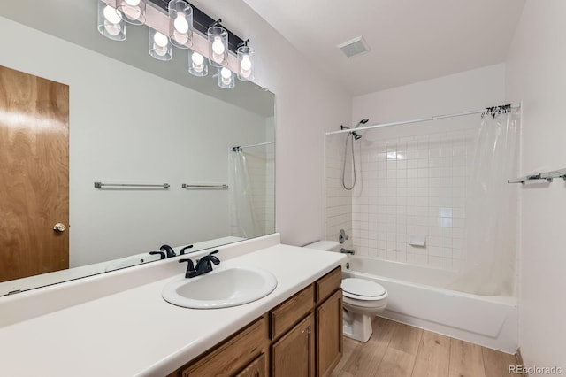 bathroom featuring shower / bath combination with curtain, visible vents, wood finished floors, vanity, and toilet