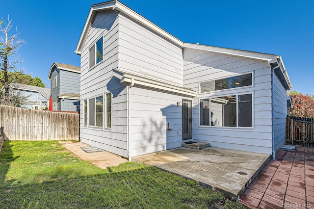 back of property featuring fence, a yard, and a patio area