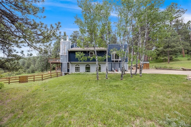 back of house featuring a lawn, a chimney, and fence