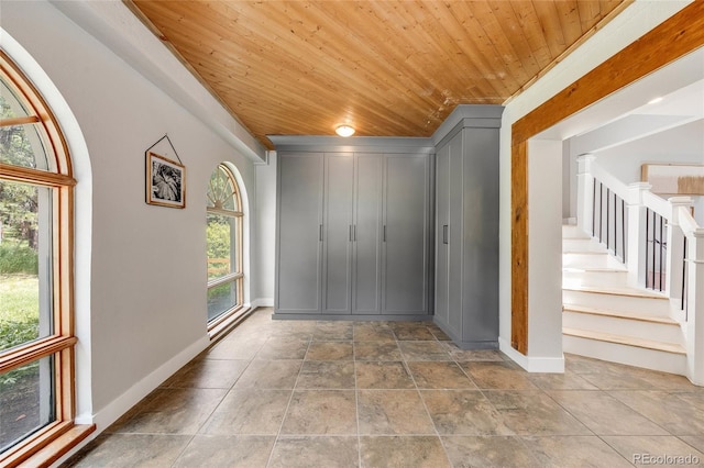 foyer entrance featuring wood ceiling, stairway, and baseboards