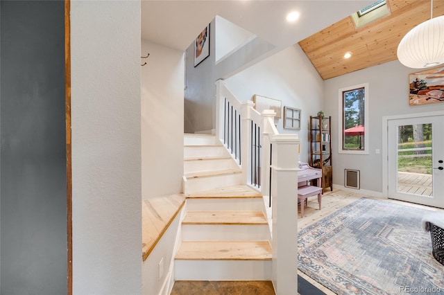 staircase featuring wood ceiling, vaulted ceiling with skylight, and recessed lighting