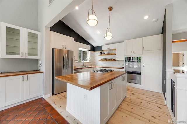 kitchen featuring lofted ceiling, light wood-style flooring, stainless steel appliances, butcher block counters, and white cabinets