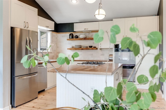 kitchen with stainless steel appliances, lofted ceiling, white cabinetry, and a kitchen island