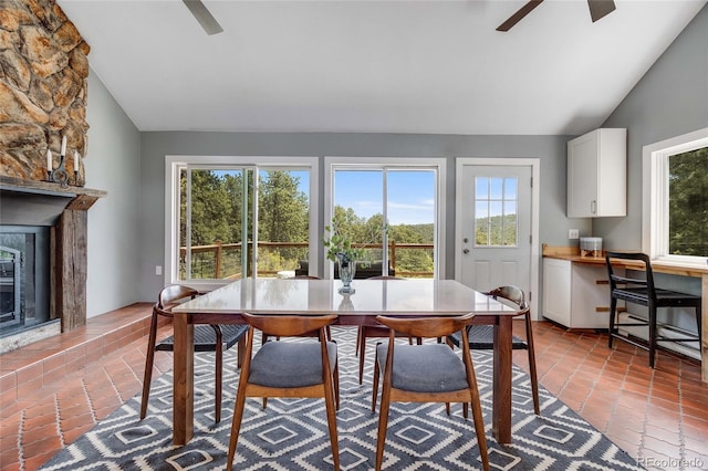 dining area featuring a ceiling fan, a glass covered fireplace, vaulted ceiling, and built in desk