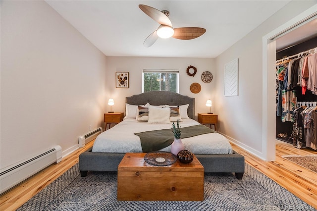 bedroom with a baseboard heating unit, light wood finished floors, a baseboard radiator, and baseboards