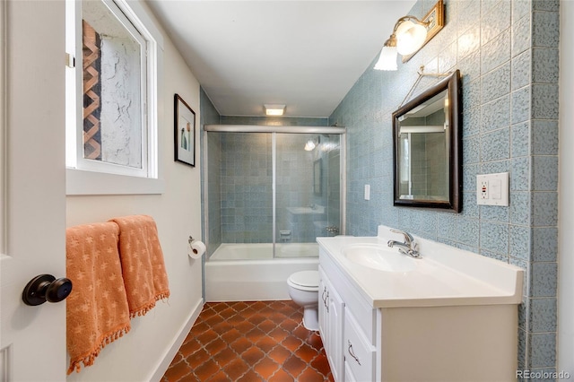 full bath with toilet, combined bath / shower with glass door, tile patterned flooring, and vanity