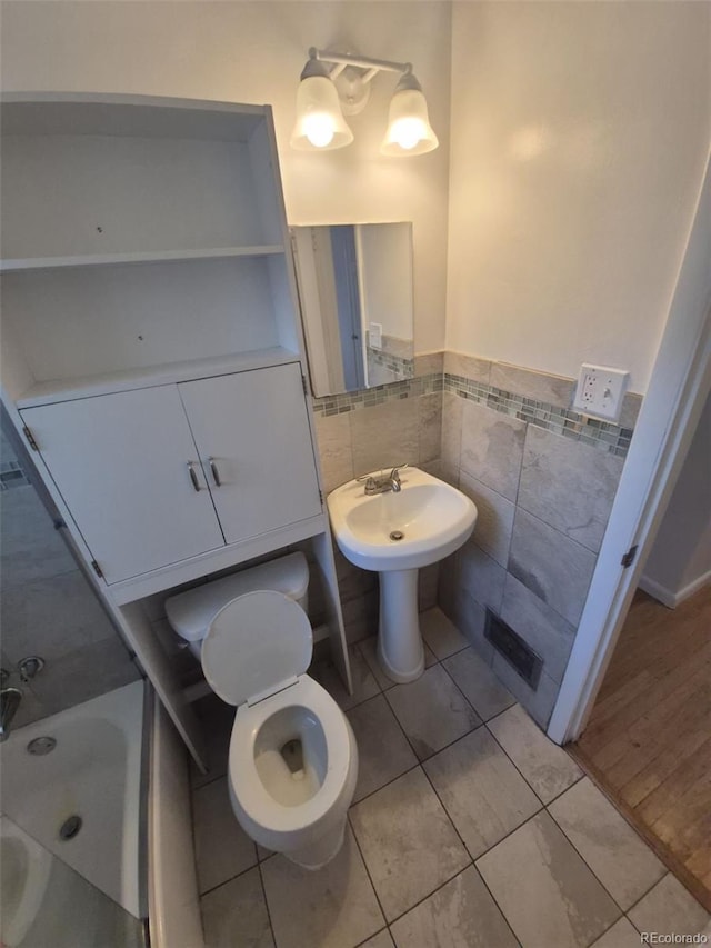 588 Empire St, Aurora, CO 80010 - full bath with tile walls, tile patterned flooring, toilet, a tub to relax in, and wainscoting