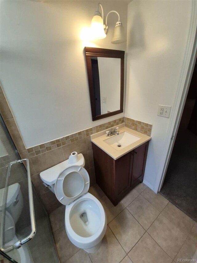 588 Empire St, Aurora, CO 80010 - bathroom with tile walls, toilet, vanity, tile patterned floors, and wainscoting