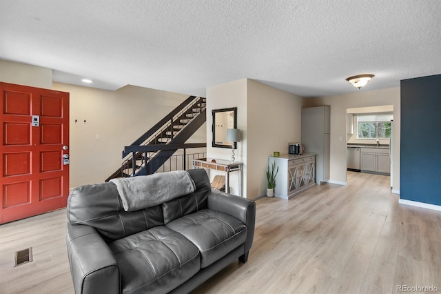 6856 S Broadway, Centennial, CO 80122 - living area featuring stairway, light wood finished floors, a textured ceiling, and baseboards