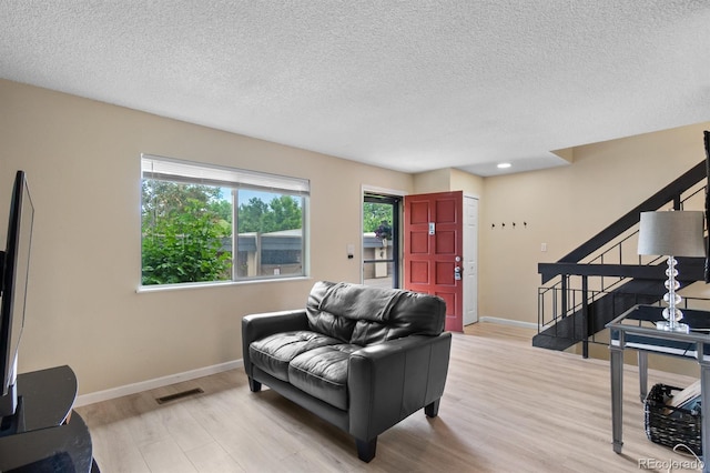 6856 S Broadway, Centennial, CO 80122 - living area featuring light wood finished floors, stairway, baseboards, and a textured ceiling
