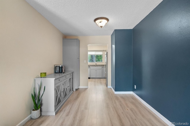 6856 S Broadway, Centennial, CO 80122 - hallway featuring light wood-style floors, a textured ceiling, baseboards, and a sink