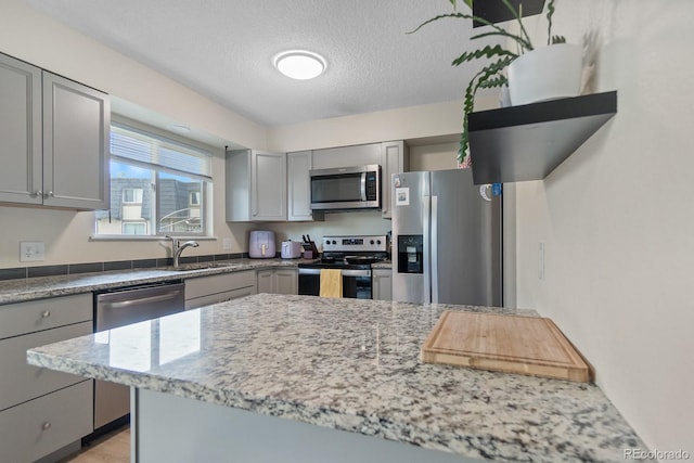 6856 S Broadway, Centennial, CO 80122 - kitchen with stainless steel appliances, gray cabinets, a sink, light stone countertops, and a textured ceiling
