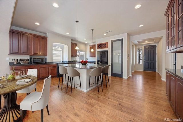 kitchen featuring pendant lighting, light wood-type flooring, black refrigerator with ice dispenser, and a center island