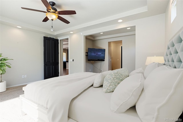 carpeted bedroom with ceiling fan and a raised ceiling