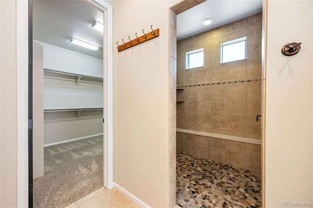 bathroom with a tile shower and tile patterned floors