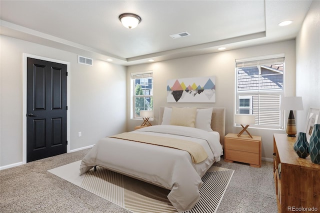 bedroom with a tray ceiling and light carpet