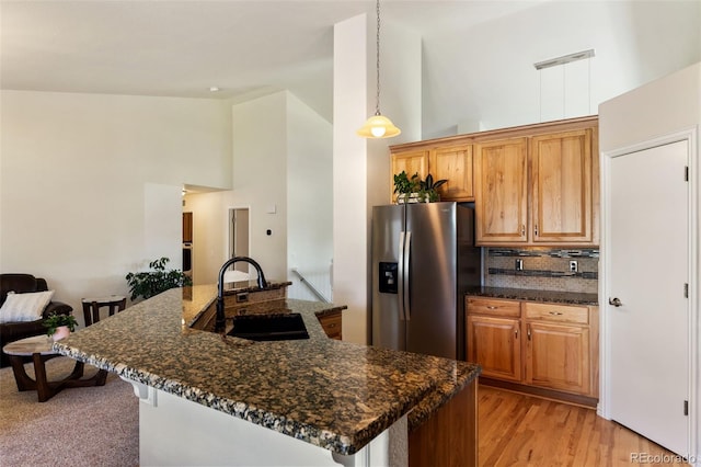 4143 Eagle Ridge Way, Castle Rock, CO 80104 - kitchen with stainless steel fridge, high vaulted ceiling, a breakfast bar, light wood-type flooring, and dark stone countertops