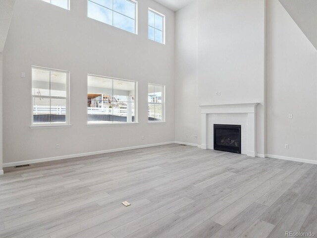 4741 Twelve Oaks Way, Castle Rock, CO 80104 - unfurnished living room featuring a high ceiling, light wood-type flooring, a glass covered fireplace, and baseboards